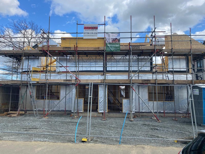 Timber-frame new build property surrounded by scaffold and temporary site fencing